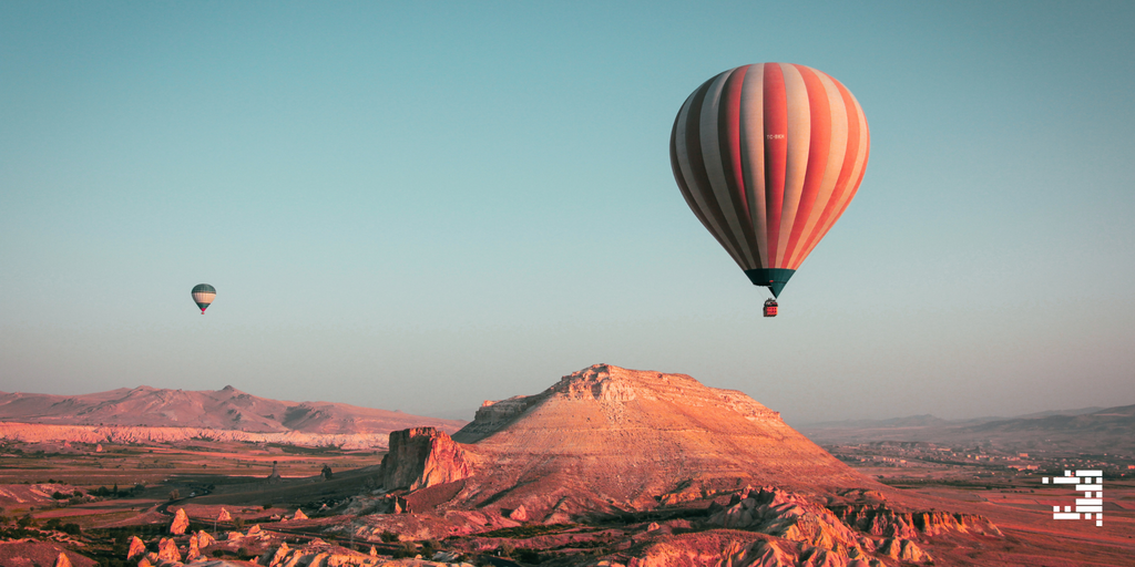 Hot air balloons over a desert landscape with mountains in the background