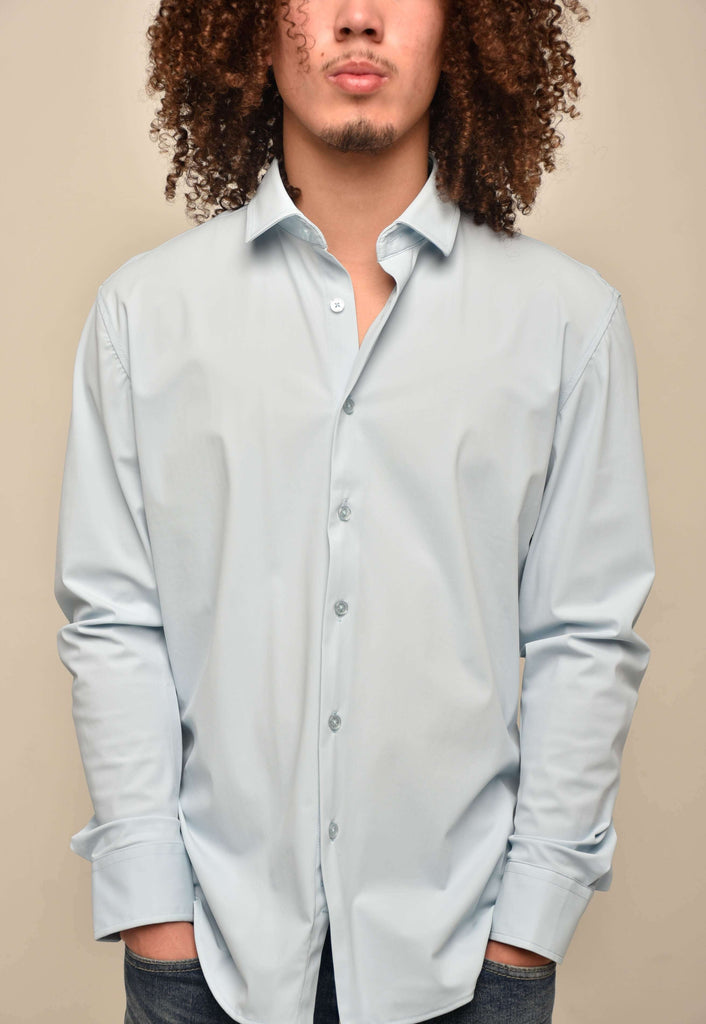 Man wearing a light blue button-up long sleeve shirt against a beige background